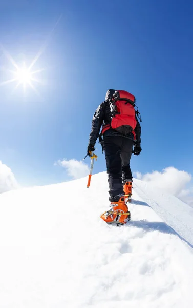 Kış mevsiminde karlı bir dağ zirvesinin zirvesine ulaşan bir dağcı. Kavram: sıkıntının üstesinden gelmek, hedeflere ulaşmak. — Stok fotoğraf