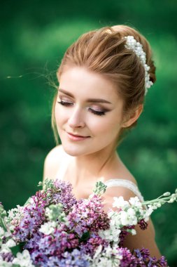 Güzel kız elle çiçek açması bir elma ağacı dalı. Genç güzel sarışın bir kadın çiçek bahçesinde. Gelin.