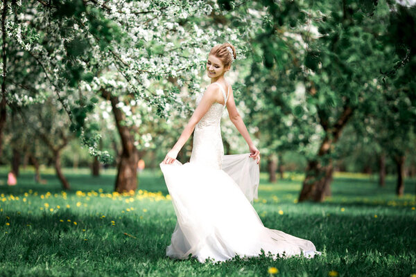 Young beautiful blonde woman in blooming garden. Young beautiful blonde woman in blooming garden. Bride.