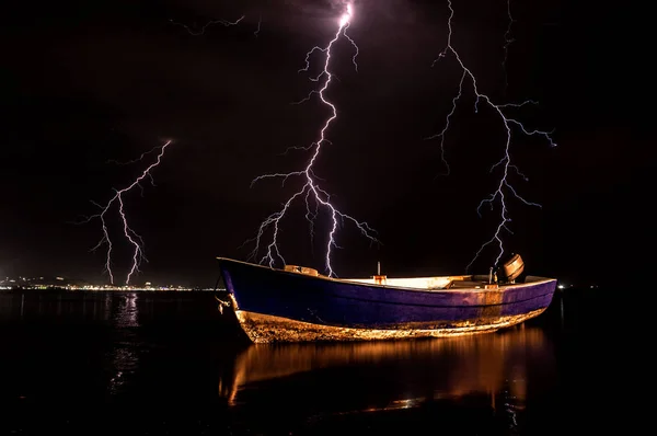 Boat on water with storm lightnings on night sky background, Durres, Albania