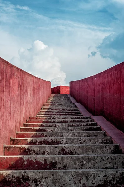 view of red stairs to clouded blue sky