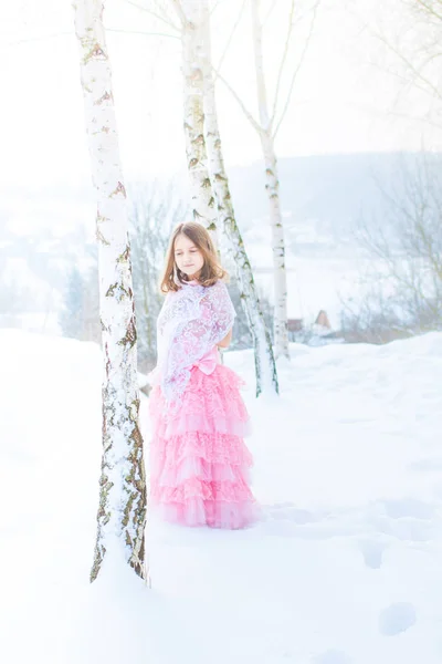 A beautiful eight years old girl walks on a frozen forest covered with snow.