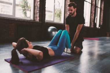 Kişisel antrenör bir kız spor egzersizleri ile yardımcı olur