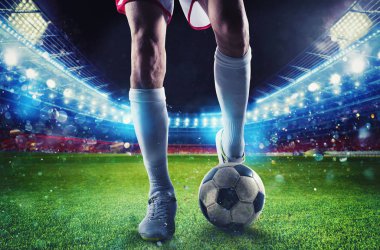 Futbol oyuncusu maç sırasında stadyumda futbol topuna vurmaya hazır.