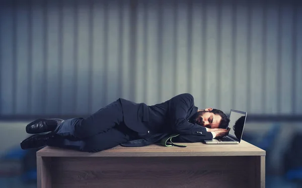 Empresario durmiendo sobre un escritorio debido al exceso de trabajo — Foto de Stock