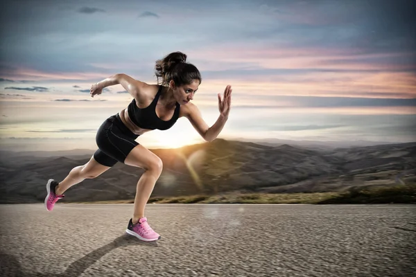 Sportliche Frau läuft bei Sonnenuntergang auf die Straße — Stockfoto