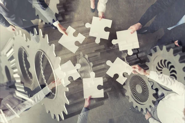 Teamwork of partners. Concept of integration and startup with puzzle pieces and gear overlay. double exposure — Stock Photo, Image