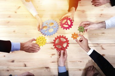 İş ekibi dişli parçalarını birbirine bağlıyor. Takım çalışması, ortaklık ve bütünleşme kavramı