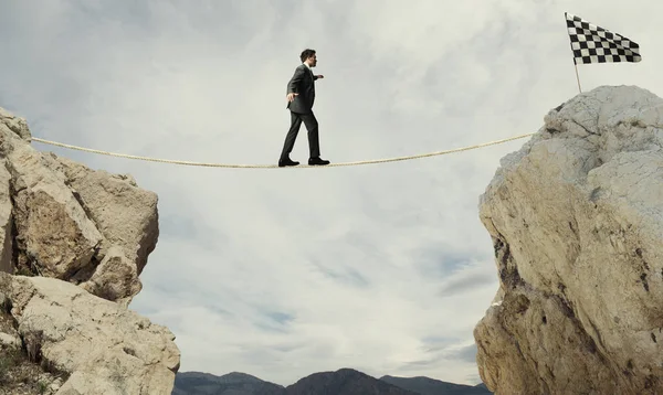 Business concept of businessman who overcome the problems reaching the flag on a rope — Stock Photo, Image