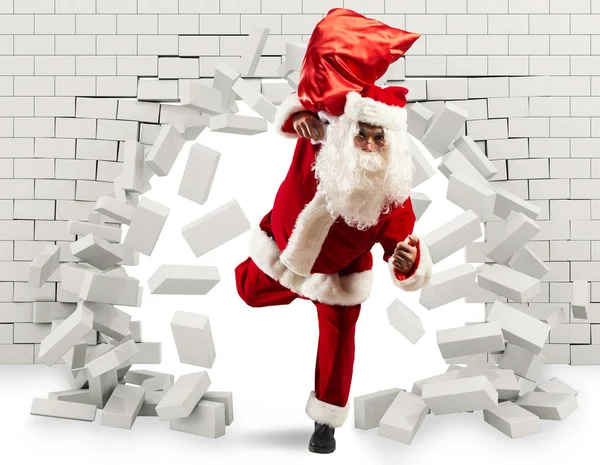 Weihnachtsmann kommt herein, um das Geschenk zu überbringen, indem er ein Loch in die Wand macht — Stockfoto