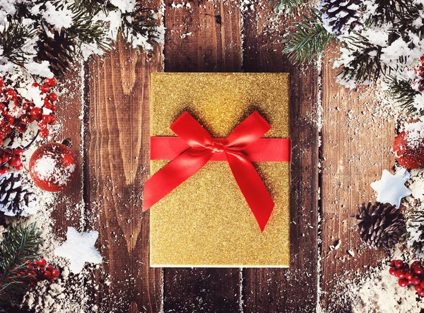 Різдвяна подарункова коробка представлена в середині різдвяних прикрас на дерев'яних дошках — стокове фото