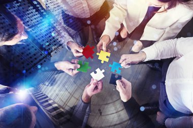 İş adamları yapboz parçalarını ofiste birleştiriyor. Takım çalışması ve ortaklık kavramı. Işık efektleri ile çift pozlama