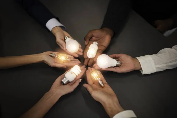 Trabajo en equipo y el concepto de lluvia de ideas con hombres de negocios que comparten una idea con una lámpara. Concepto de startup — Foto de Stock