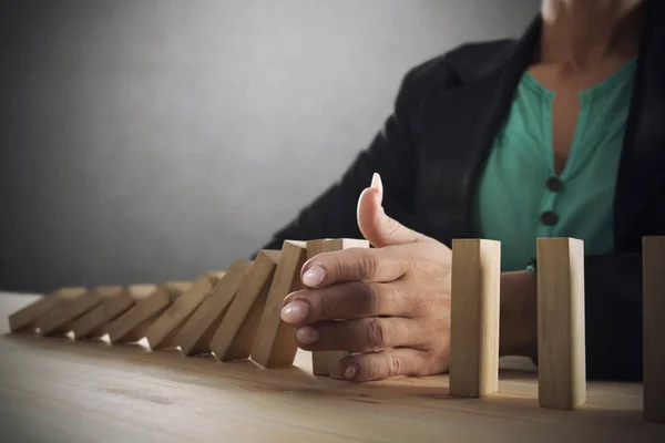 Femme d'affaires arrête une chute de chaîne comme jeu domino. Concept de prévention des crises et des faillites dans les entreprises — Photo