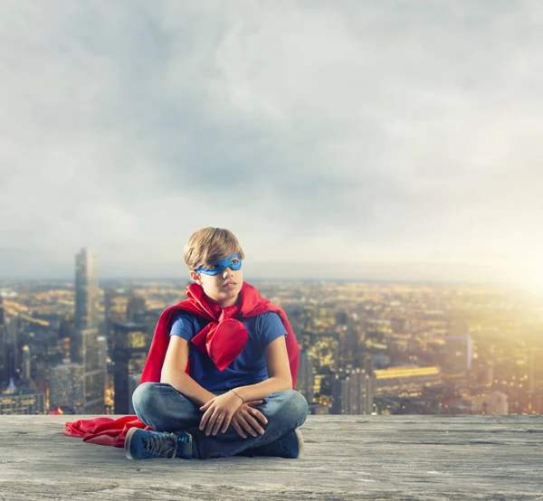 Superhero dziecko siedzi na ścianie, który marzy — Zdjęcie stockowe