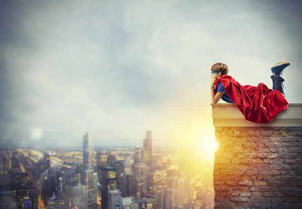 Superhero kid sitting on a wall that dreams — Stock Photo, Image