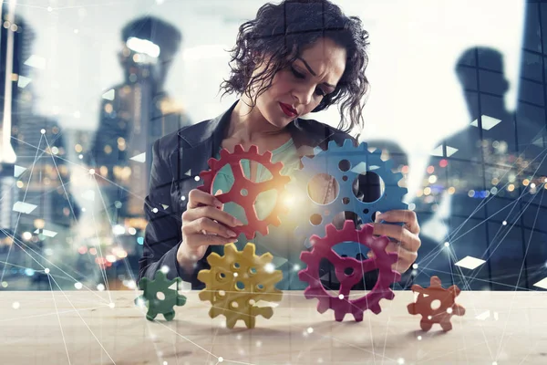 Businesswoman tries to connect gears pieces. Concept of Teamwork, partnership and integration. double exposure — Stock Photo, Image