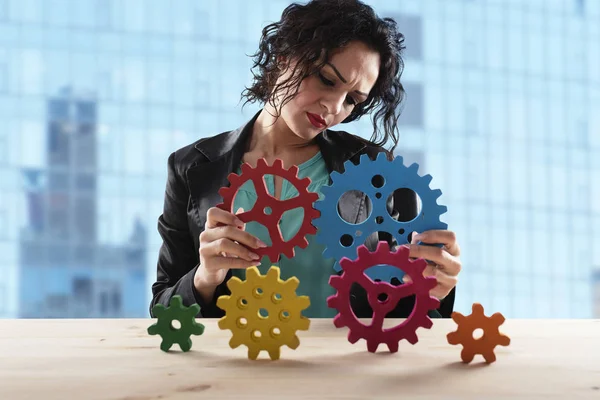 Mujer de negocios trata de conectar piezas de engranajes. Concepto de trabajo en equipo, asociación e integración — Foto de Stock