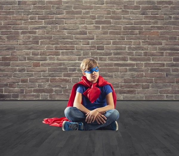 Un enfant super-héros assis sur un mur qui rêve — Photo