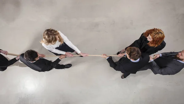 竞争对手的商人和女人通过拉绳子争夺指挥权 — 图库照片