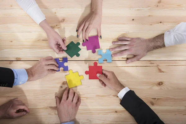 Zakenmensen voegen zich bij puzzelstukjes op kantoor. Concept van teamwork en partnerschap — Stockfoto