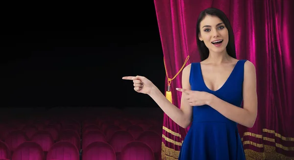 Mulher bonita na frente de cortinas vermelhas indica algo sobre o show de teatro — Fotografia de Stock