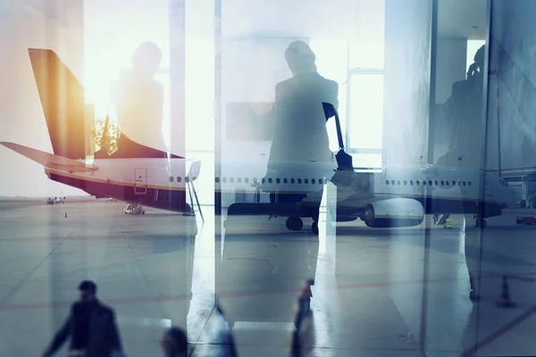 Silhouetten von Geschäftsleuten am Flughafen, die auf das Boarding warten. Doppelbelastung — Stockfoto