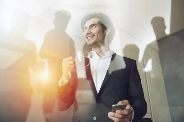 Geschäftsmann arbeitet im Büro mit seinem Smartphone. Doppelbelastung. — Stockfoto