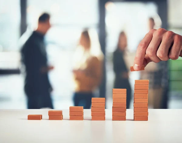 El hombre de negocios pone un ladrillo en una pila de ladrillos. Concepto de crecimiento de las estadísticas y éxito — Foto de Stock