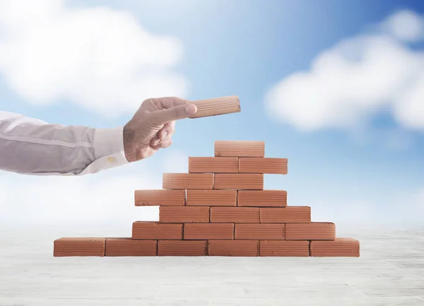 Un homme d'affaires met une brique pour construire un mur. Concept de nouvelle entreprise, de partenariat, d'intégration et de démarrage — Photo