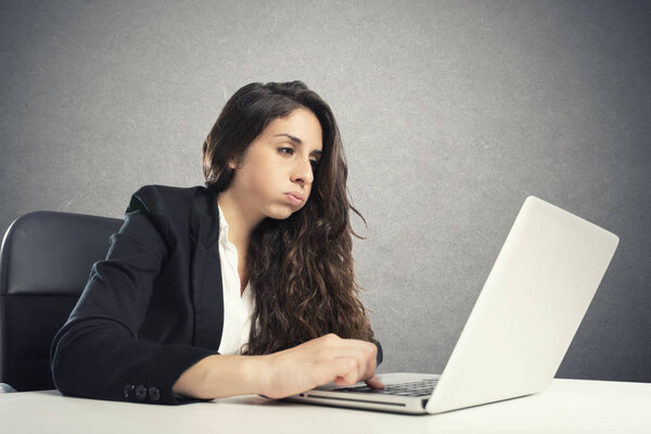 Bored woman snorts in the office while working on the laptop