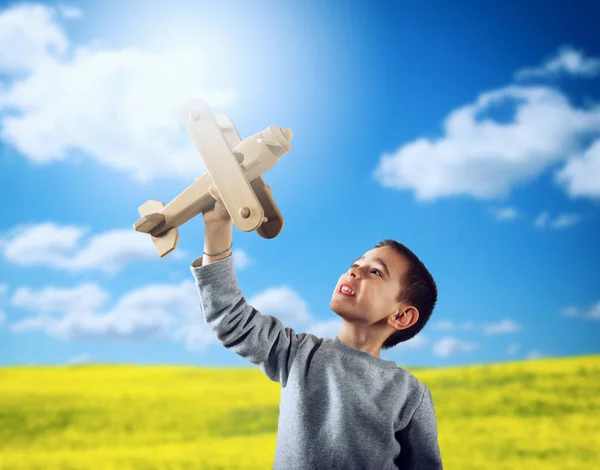 Kid plays with a wooden toy airplane — Stock Photo, Image