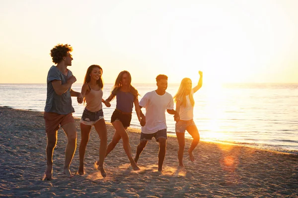 Grupo de amigos felizes se divertindo na praia do oceano ao amanhecer — Fotografia de Stock
