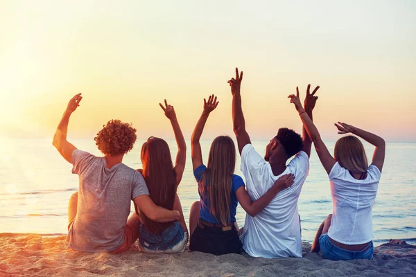 Grupp av glada vänner att ha kul på ocean beach i gryningen — Stockfoto