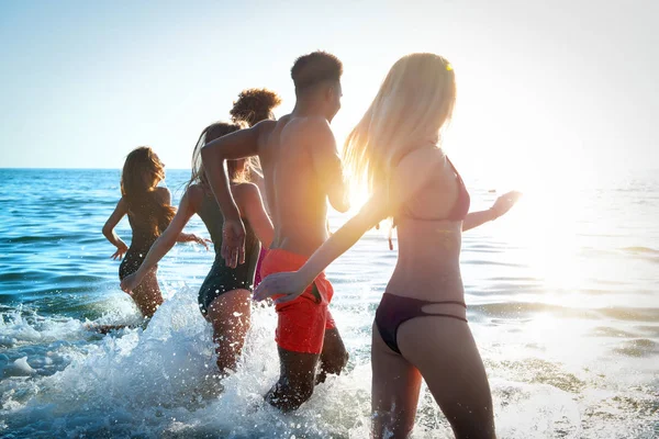 Un grupo de amigos corre en el mar. Concepto de verano — Foto de Stock