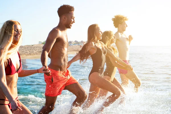 Un grupo de amigos corre en el mar. Concepto de verano — Foto de Stock