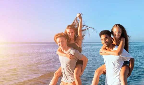 Felices parejas sonrientes jugando en la playa — Foto de Stock