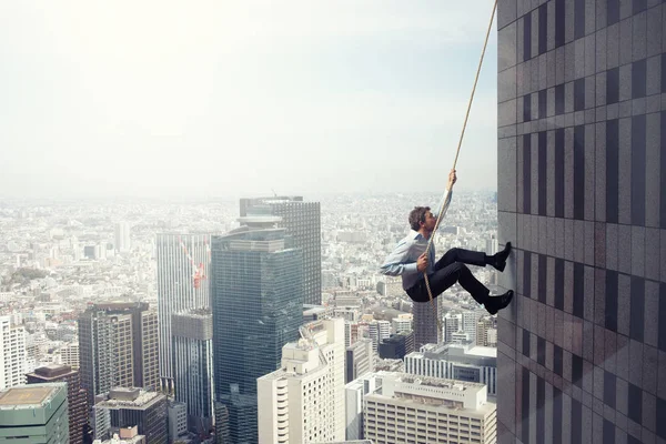 L'uomo d'affari sale su un edificio con una corda. Concetto di determinazione — Foto Stock