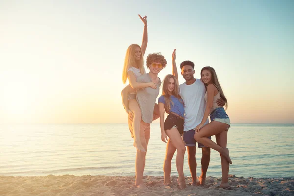 Skupina happy přátelé baví na pláži u oceánu za svítání — Stock fotografie