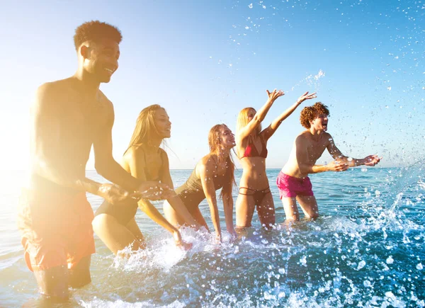 Grupo de amigos divirtiéndose en la playa con mar de agua — Foto de Stock