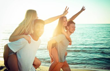 Mutlu gülümseyerek kumsalda oynarken çiftler