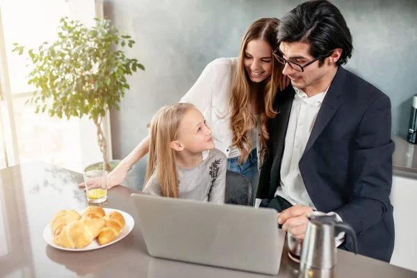 Gelukkig klein meisje kijken naar een film op de computer met haar vader en moeder — Stockfoto