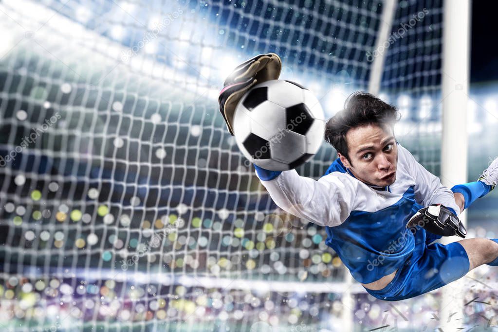 Goalkeeper catches the ball in the stadium during a football game.