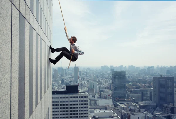 Un homme d'affaires grimpe un immeuble avec une corde. Concept de détermination — Photo