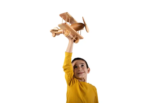 El chico juega con un avión de juguete de madera. Aislado sobre fondo blanco — Foto de Stock