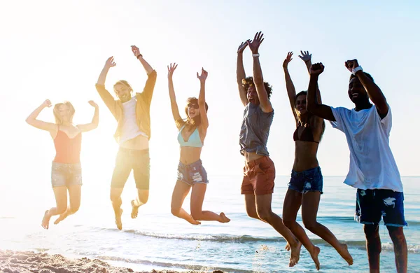 Glücklich lächelnde Freunde springen am Strand — Stockfoto
