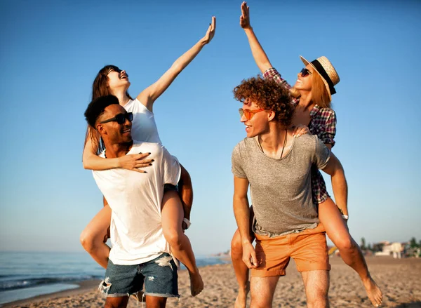 Felices parejas sonrientes jugando en la playa — Foto de Stock