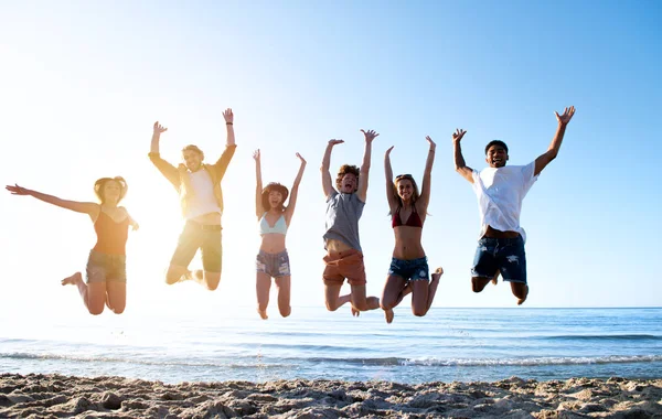 Felizes amigos sorridentes pulando na praia — Fotografia de Stock