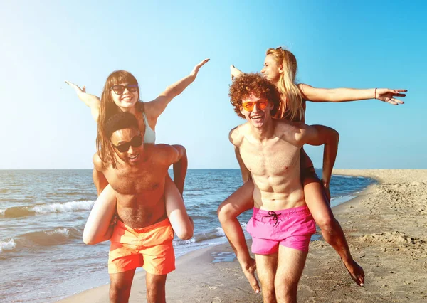 Felices parejas sonrientes jugando en la playa — Foto de Stock