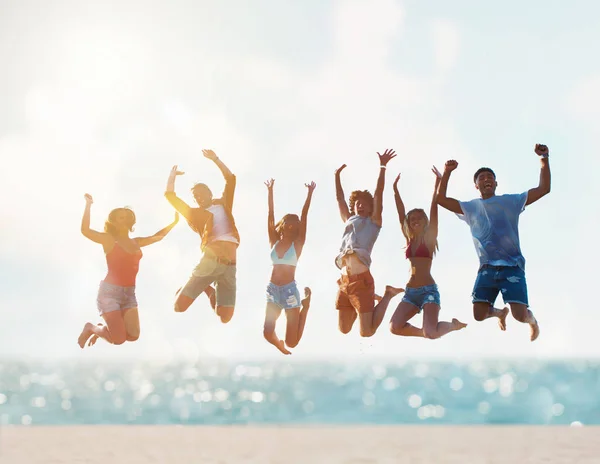 Happy lachende vrienden springen op het strand — Stockfoto